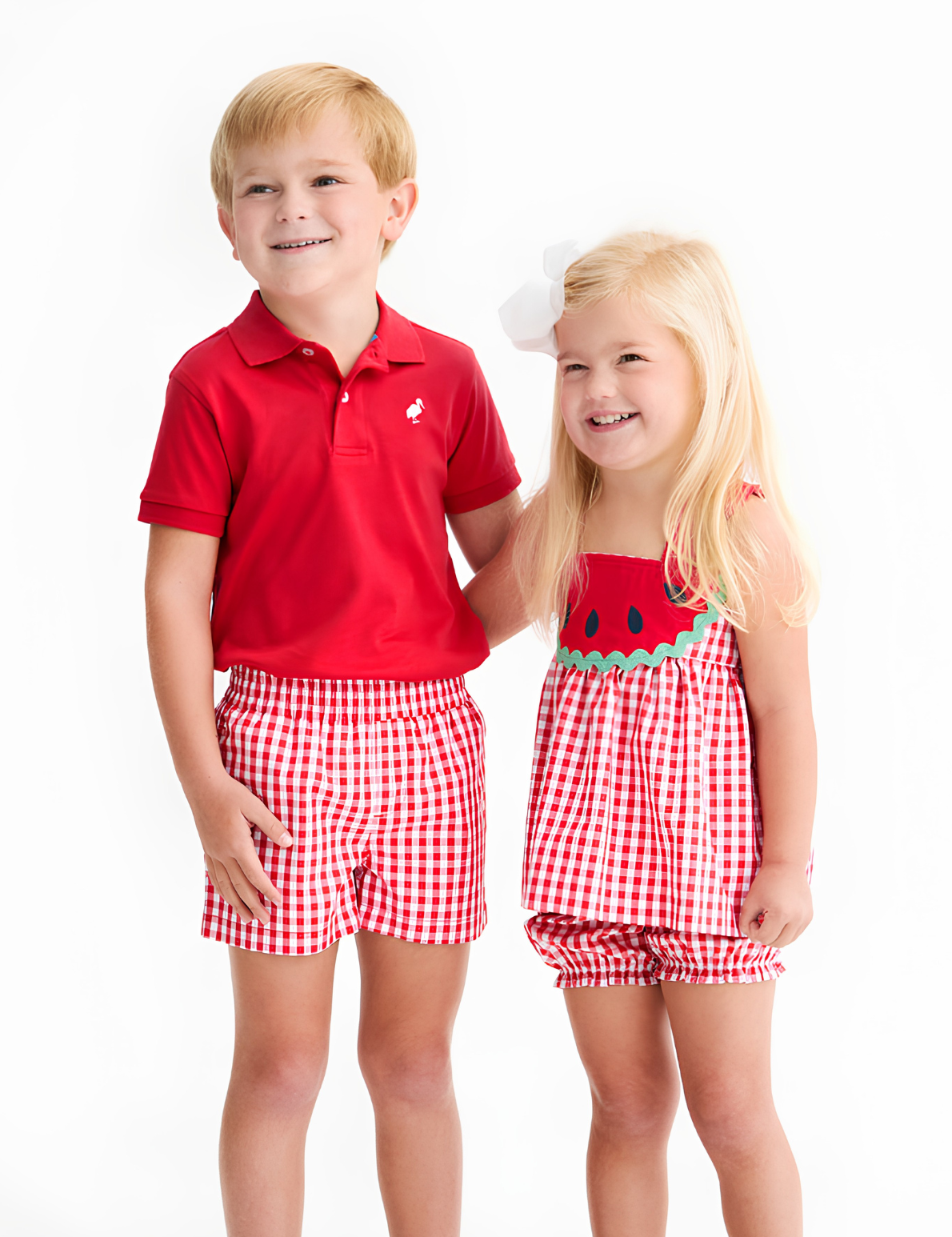 Two children wearing matching red and white checkered outfits on a white background